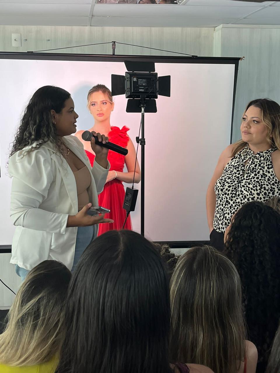 Mentora apresentando técnica de maquiagem com microfone durante a aula